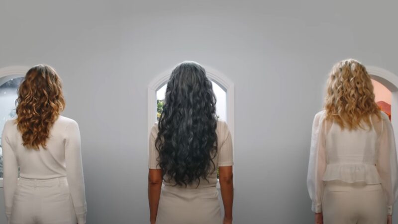 Three girls with different hair colors standing in front of the wall